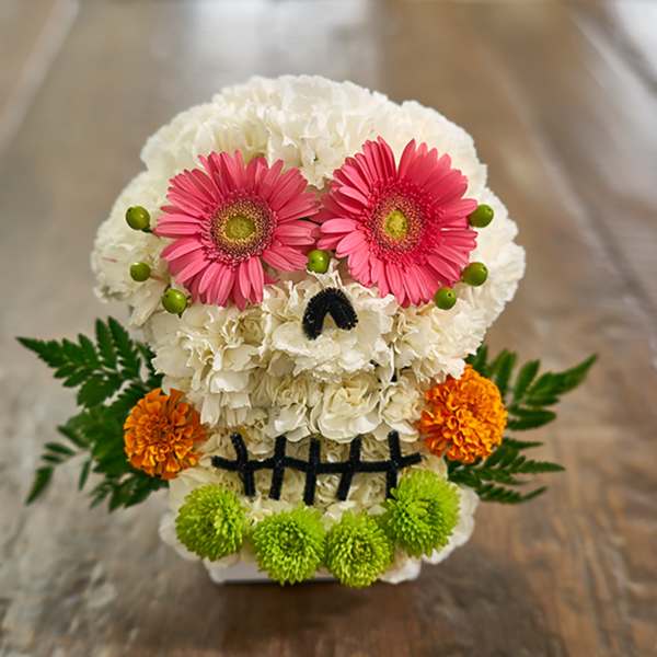 Skull-shaped floral arrangement with pink daisies and white blooms