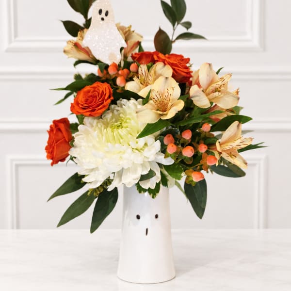 Orange and white flower arrangement in a white ghost vase
