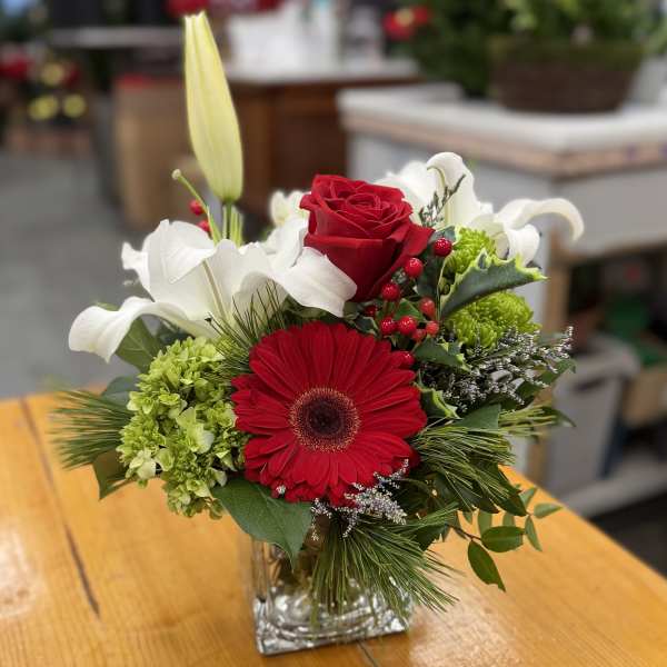 Red gerbera and rose bouquet in a clear square vase