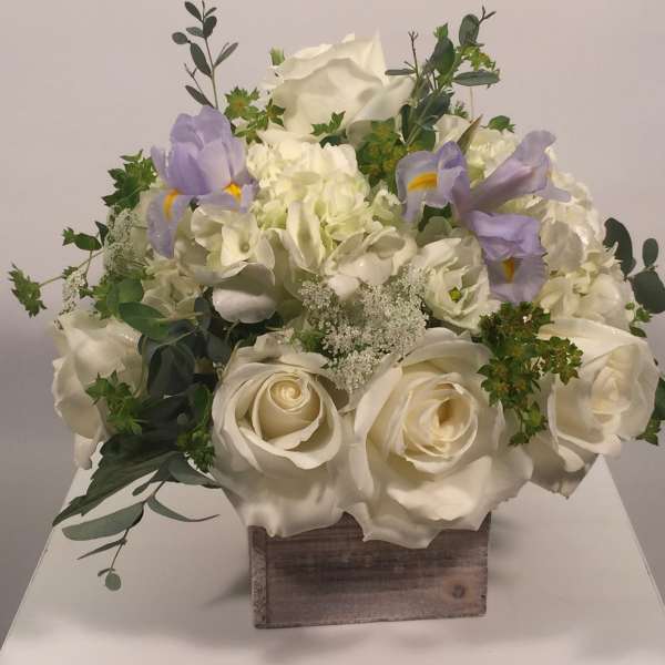 White rose and hydrangea arrangement with lavender irises in a wooden box