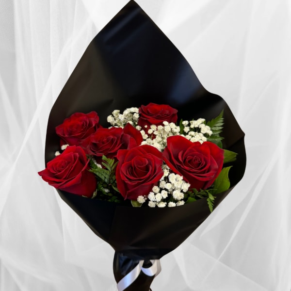 Bouquet of red roses with white filler flowers wrapped in black paper and ribbon