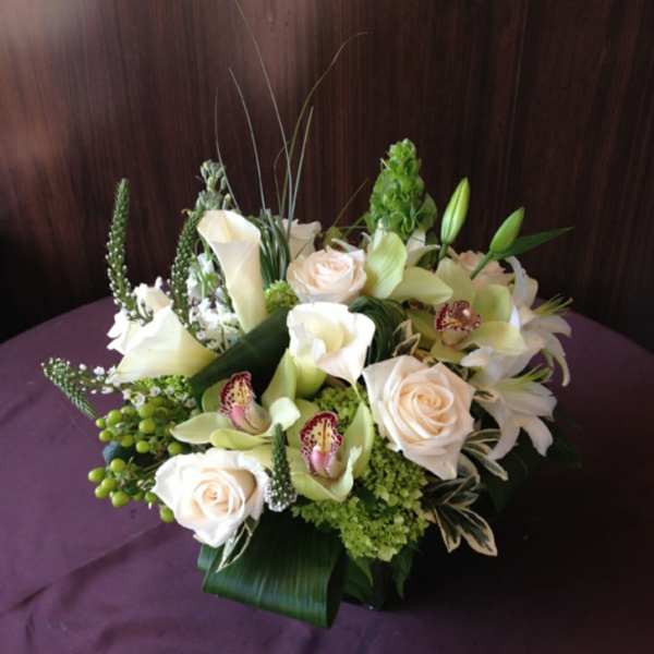 Cream roses and white calla lilies arranged in a low bouquet