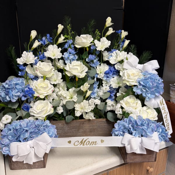 White and blue floral arrangement in a wooden box with ribbon bows