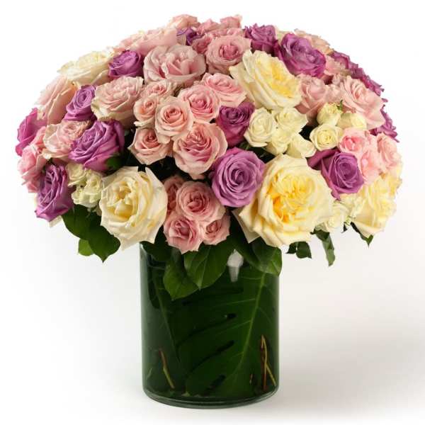 Large dome of pastel roses in a leaf-lined glass cylinder vase