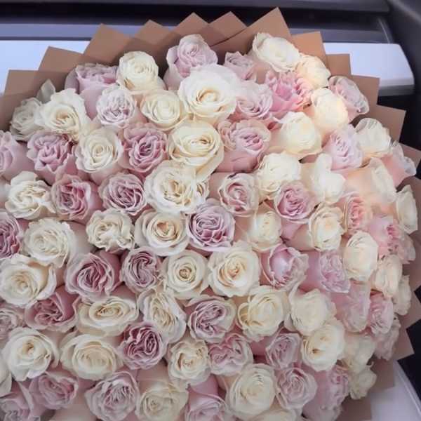 Large bouquet of pale pink and white roses wrapped in brown paper