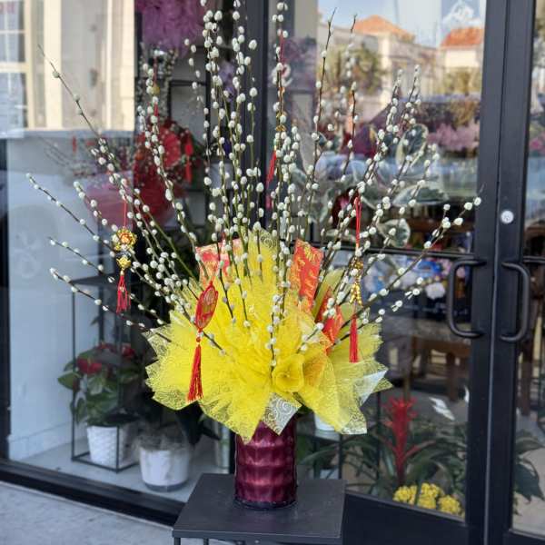 Tall decorative arrangement with pussy willow branches and yellow wrapping in a vase