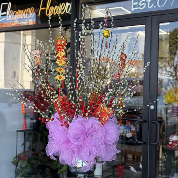 Tall decorative arrangement of pussy willow branches with red berries in a silver vase