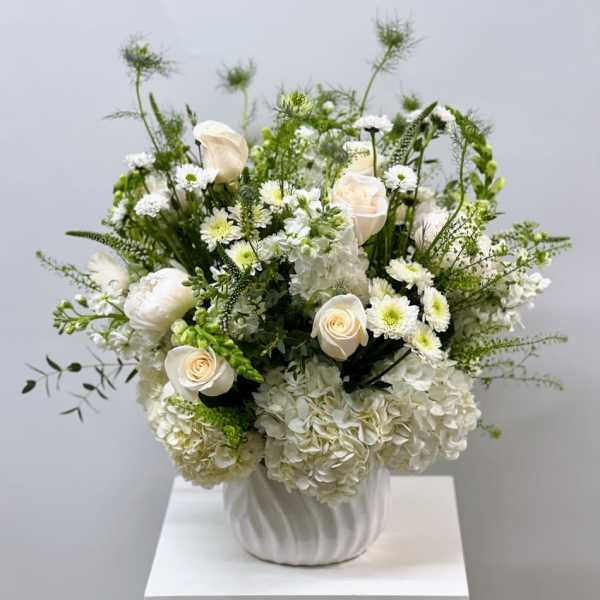 White roses and hydrangeas arranged in a white vase