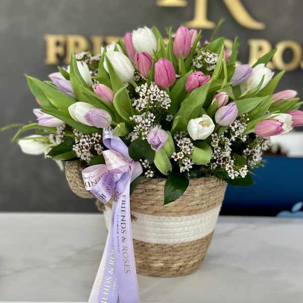 Basket arrangement of pink, white, and lavender tulips with a ribbon