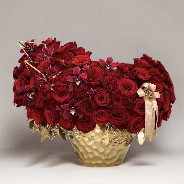 Red rose arrangement in a gold textured vase with ribbon accents
