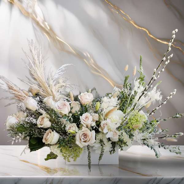 Large white floral arrangement with pale roses in a rectangular vase