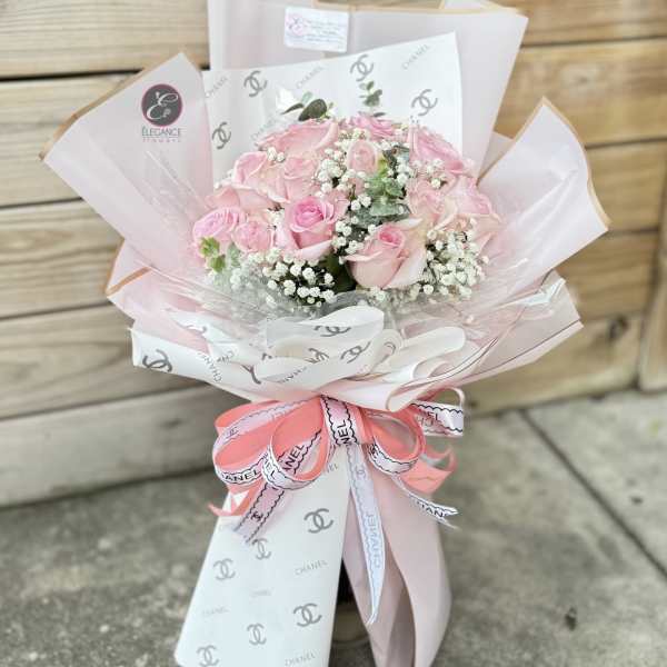 Pink rose bouquet wrapped in pale paper with a ribbon bow