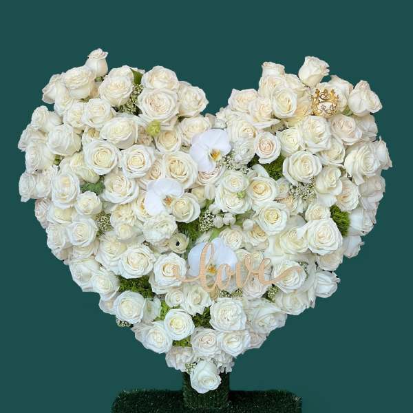 Heart-shaped white rose arrangement with a "love" sign