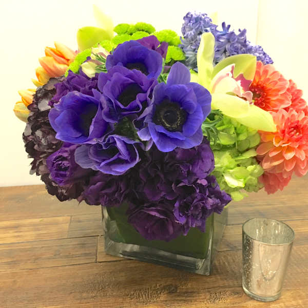 Colorful bouquet of mixed flowers in a square glass vase