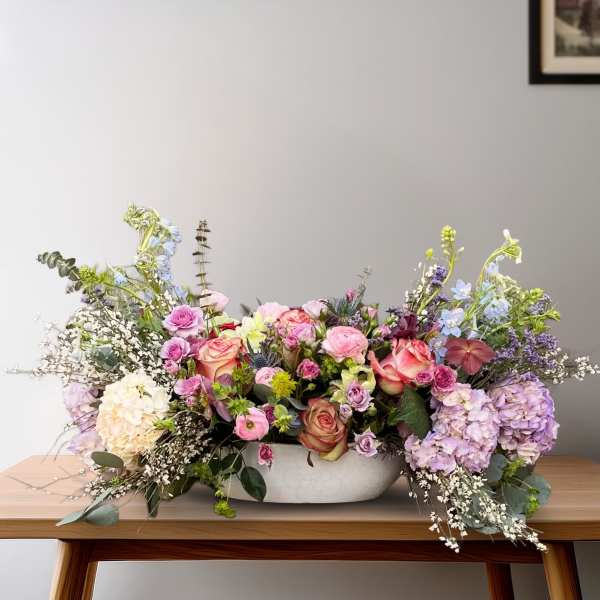 Low floral centerpiece with pink and lavender blooms in a white bowl vase