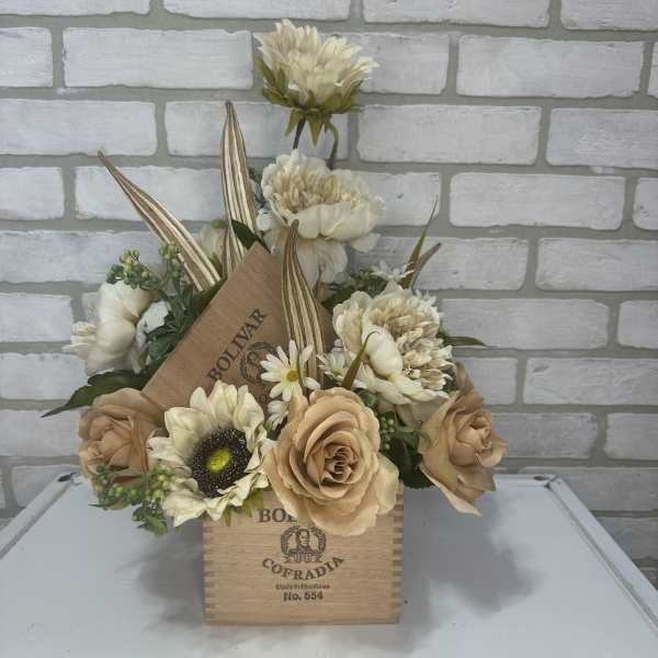 Cream and tan floral arrangement in a wooden cigar box