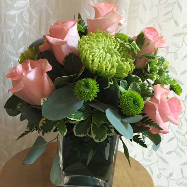Pink roses and green chrysanthemums in a square glass vase