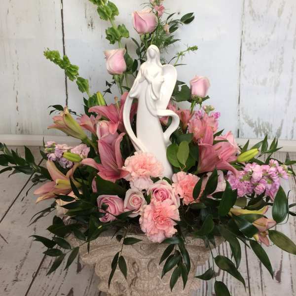 Pink floral arrangement with a white angel figurine centerpiece