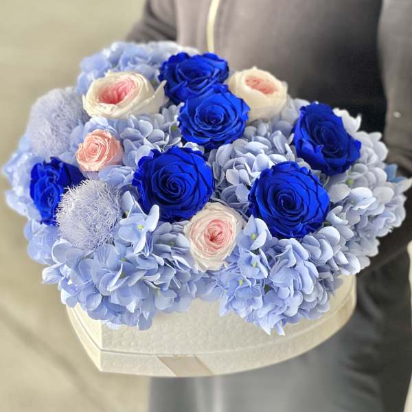 Blue and white roses arranged with pale blue hydrangeas in a heart-shaped box