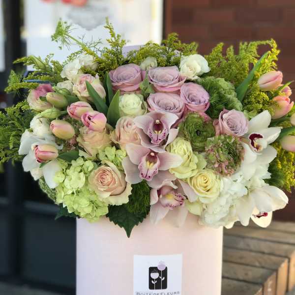 Pastel bouquet of roses, orchids, and hydrangeas in a pink hatbox