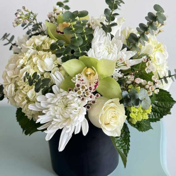 White and green floral arrangement in a black vase