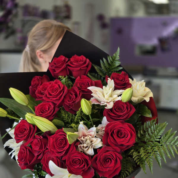 Bouquet of red roses and white lilies wrapped in black paper