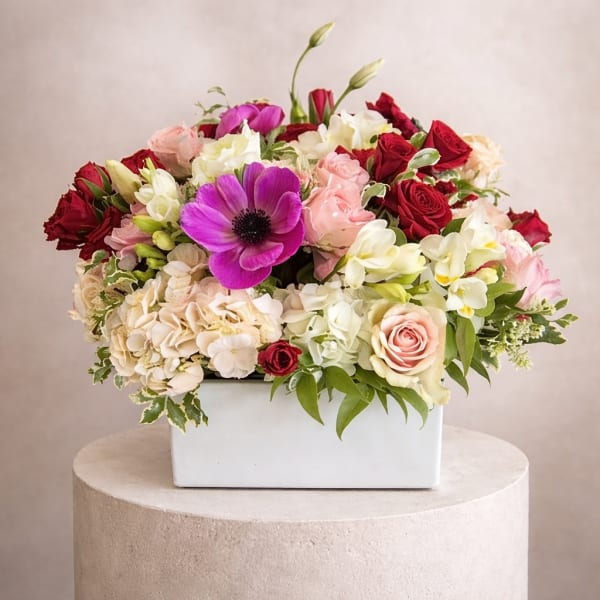 Mixed bouquet in a white rectangular vase with red, pink, white, and purple blooms