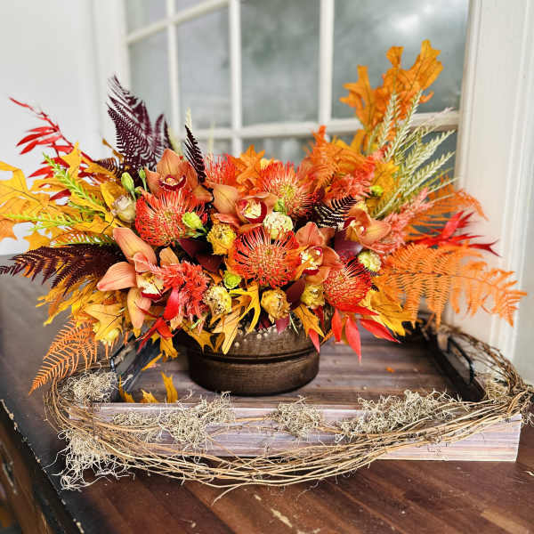 Autumn floral arrangement in a brown bowl with orange and red blooms