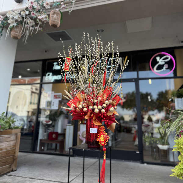 Tall red and gold floral display with pussy willow branches and hanging ornaments