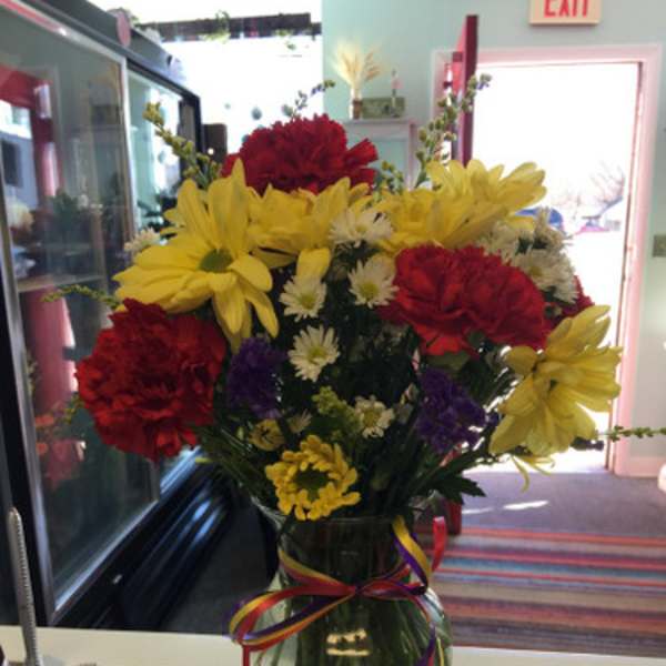 Bouquet of red and yellow flowers in a glass vase with ribbon