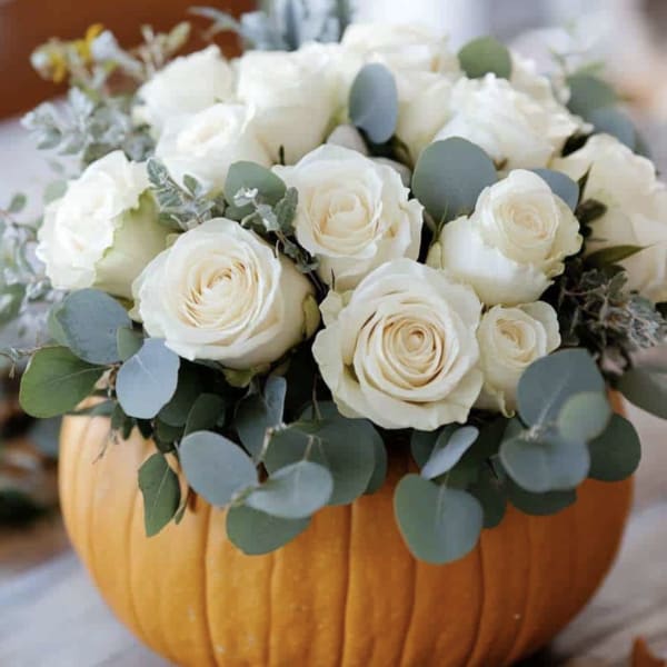 White roses arranged in a carved pumpkin centerpiece