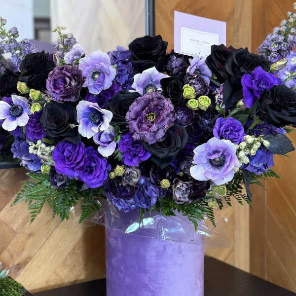 Purple and black floral arrangement in a lavender box