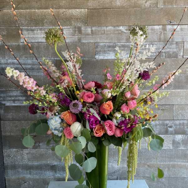 Tall mixed bouquet in a glass vase with pink, peach, and white flowers