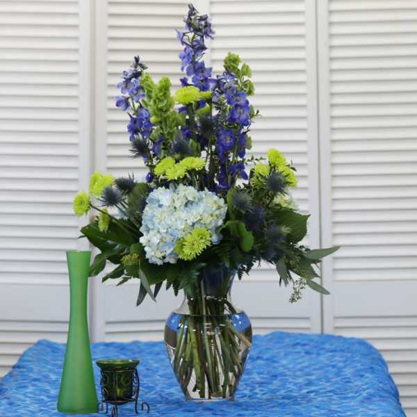 Blue and green floral arrangement in a clear glass vase