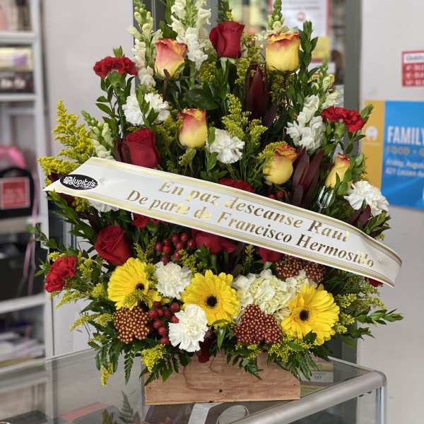 Large sympathy spray with red and yellow flowers and a memorial ribbon