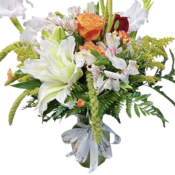 Mixed bouquet of white lilies, roses, and alstroemeria in a glass vase