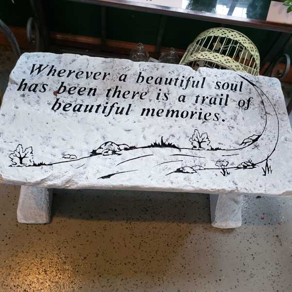 Decorative stone bench with a memorial quote painted on it