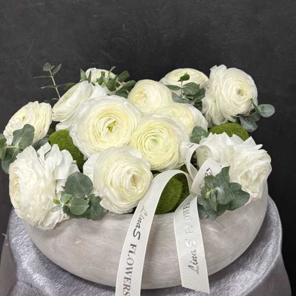 White ranunculus arrangement in a round vase with eucalyptus and ribbon