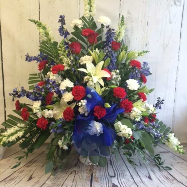 Large floral spray with red, white, and blue flowers in a blue ribbon wrap