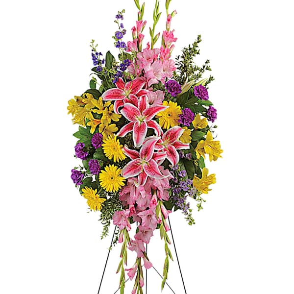 Standing floral spray with pink lilies, yellow daisies, and purple accents
