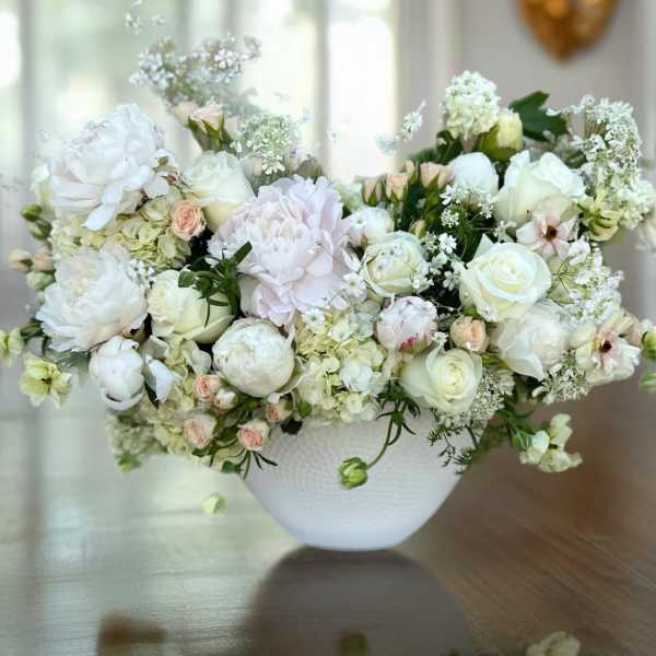White and blush floral arrangement in a white bowl vase