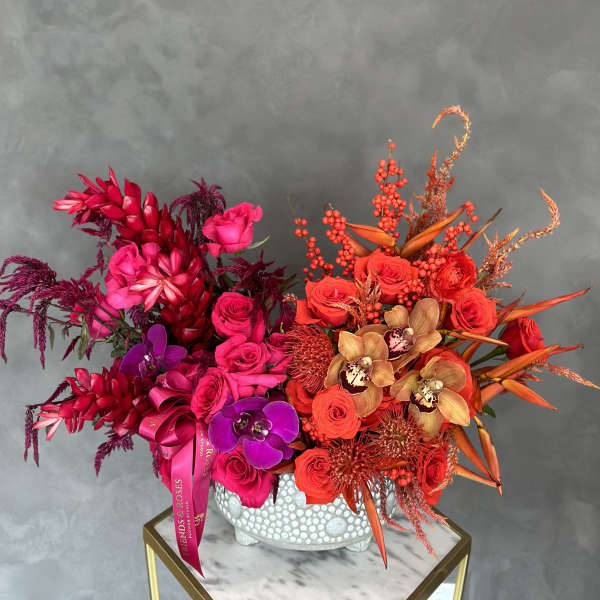 Bright red and pink floral arrangement in a white textured vase