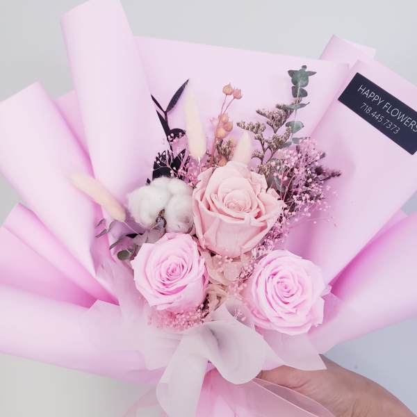 Pink rose bouquet wrapped in pastel paper with a white ribbon