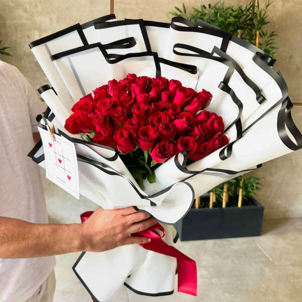 Bouquet of red roses wrapped in white paper with black trim