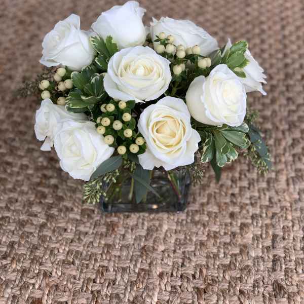 White rose bouquet in a square glass vase with berry accents