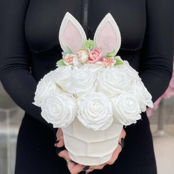 White rose arrangement in a white vase with pink bunny ears