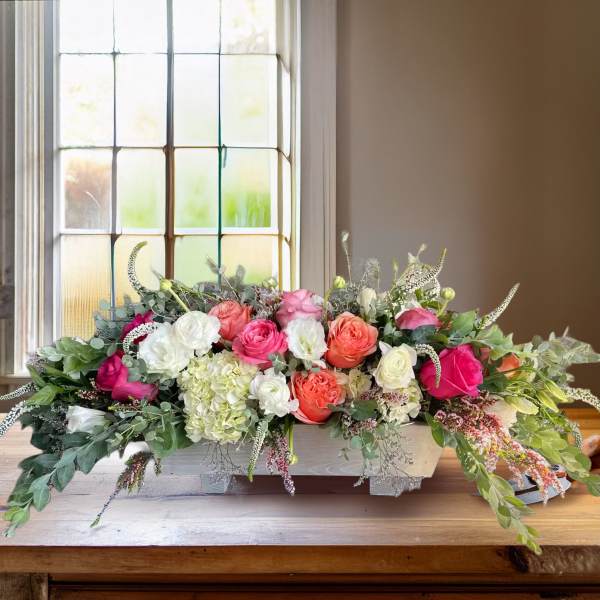 Low floral centerpiece with pink, coral, and white roses in a rectangular container