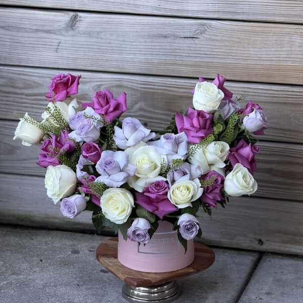 Pink and lavender roses arranged in a round pink box