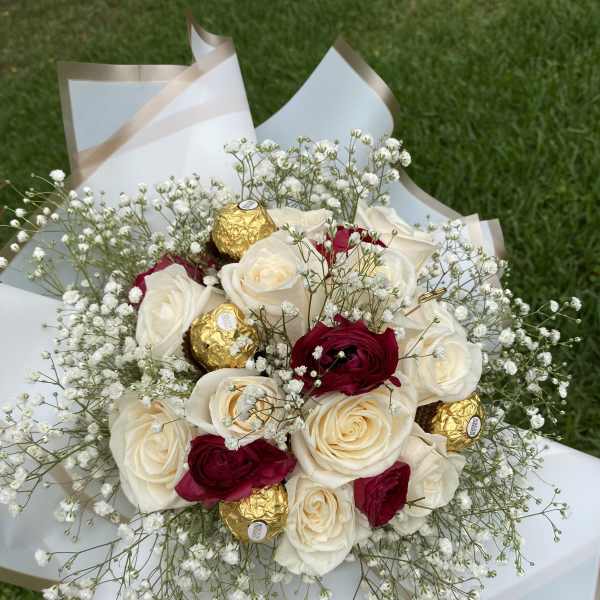 Bouquet of white and red roses with baby’s breath and gold-wrapped chocolates