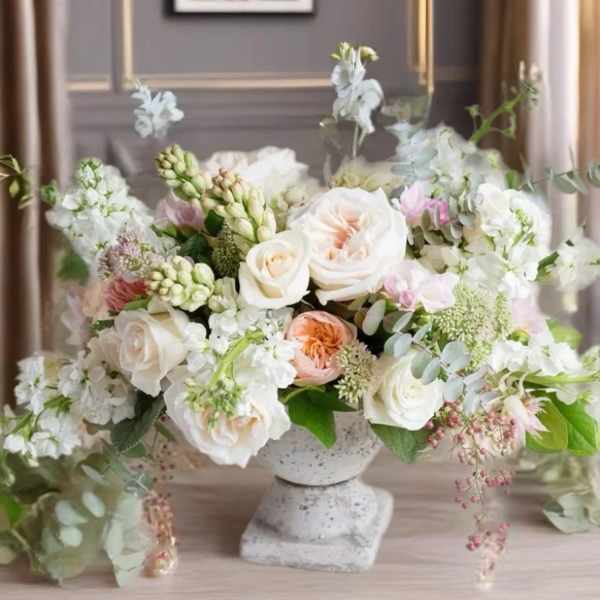 Pastel floral arrangement in a stone pedestal vase